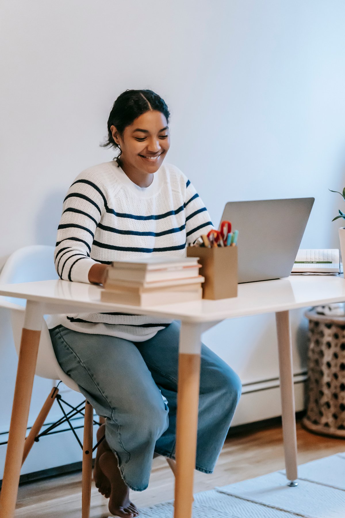 Indian lady working remotely on laptop at table in room